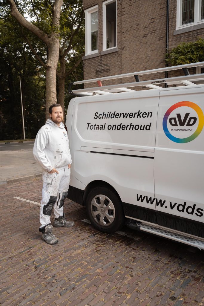 Schilder naast schilderbus op straat geparkeerd